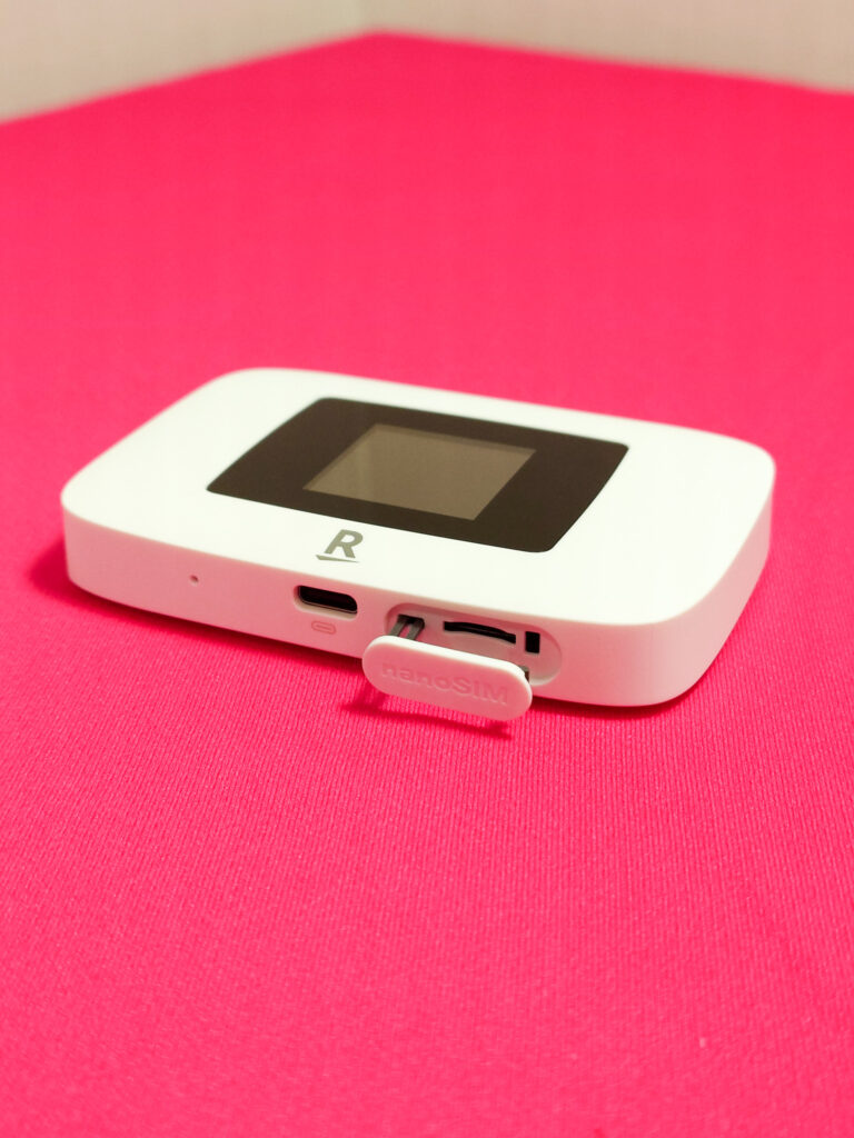 Rakuten WiFi Pocket Platinumの側面。SIMスロットが開いており、ナノSIMカードの挿入部分が表示されている赤い背景の画像。