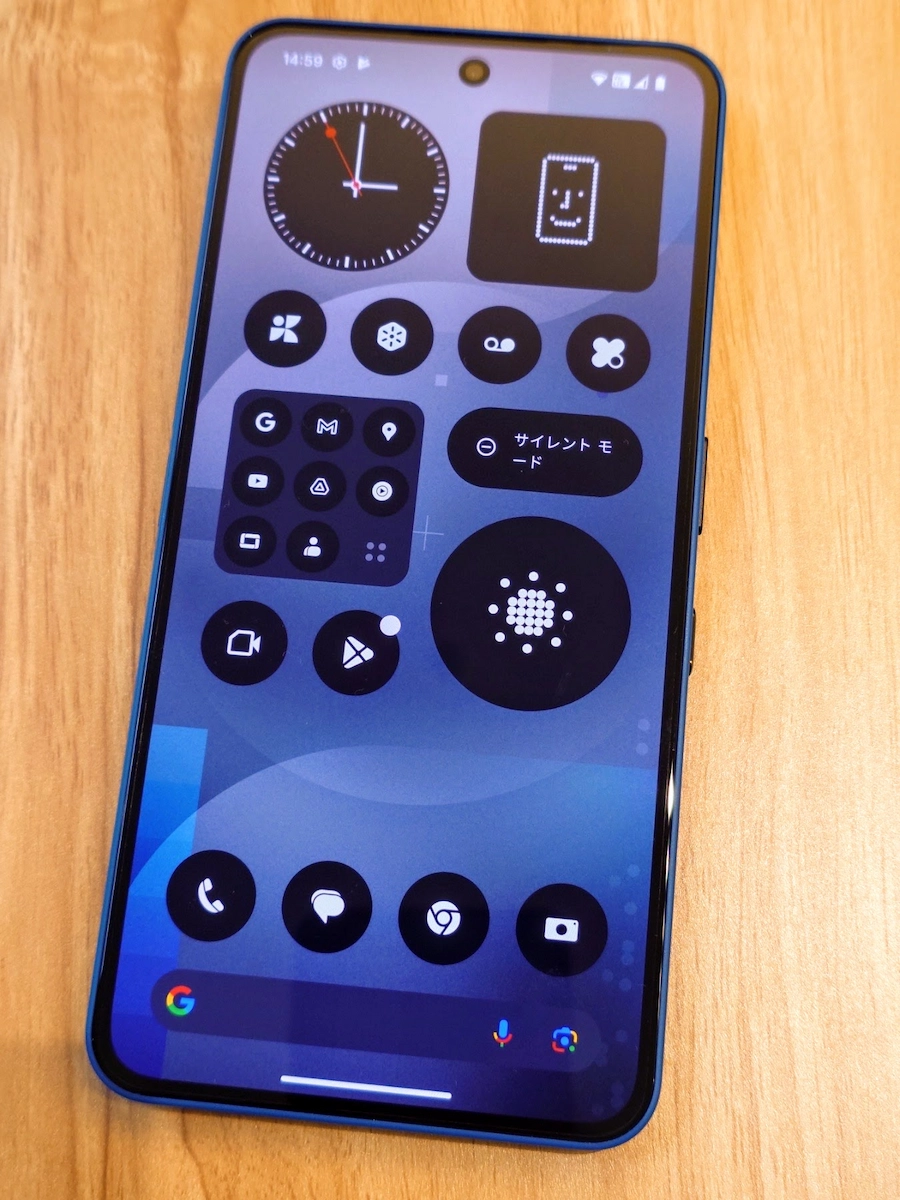 Nothing Phone (3a)ブルーのホーム画面を木製デスク上で撮影し操作イメージを伝えるシーン