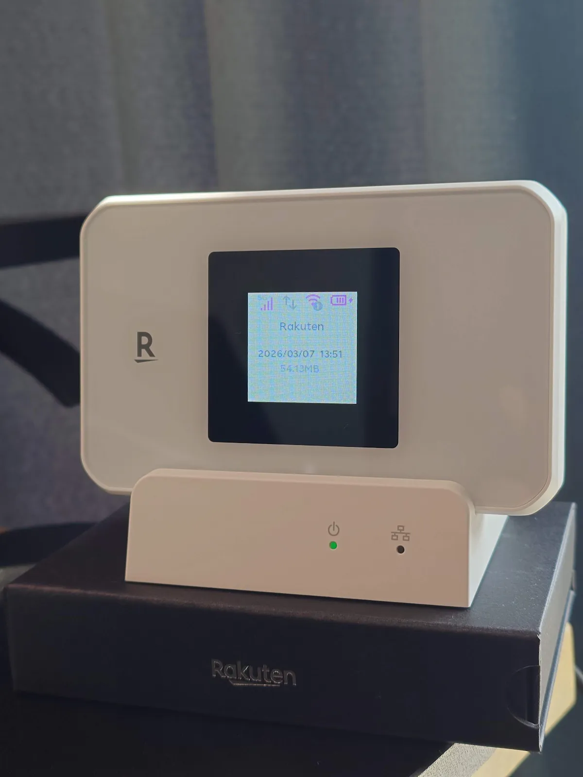 Rakuten WiFi Pocket 5Gを専用スタンドに置いて起動画面を表示した写真